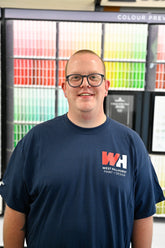 Nick Gehring, ICCP, colour consultant at West Hillhurst Paint & Design, standing at the Benjamin Moore colour wall